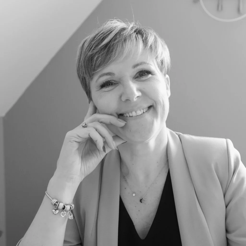 Photo représentant Véronique robillard à son bureau main contre la joue qui sourit en noir et blanc